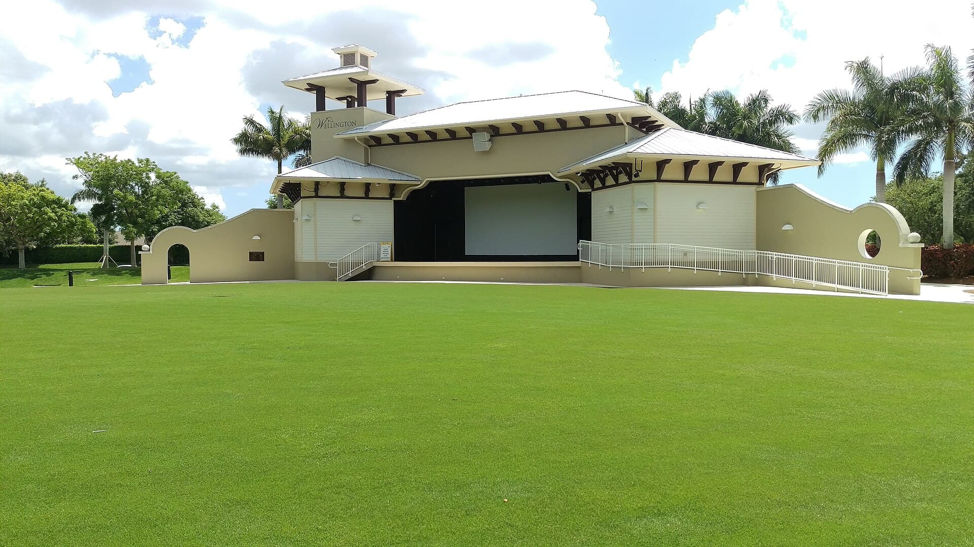 The Wellington Amphitheater seen across its lawn, with palm trees and summer clouds, Wellington, Florida